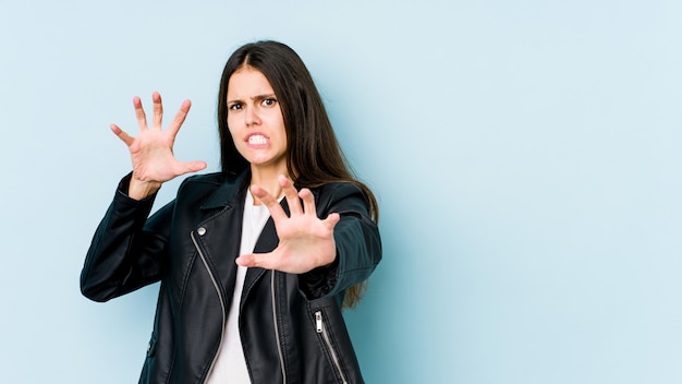 Jonge blanke vrouw op blauwe muur boos schreeuwen met gespannen handen.