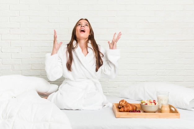 Jonge blanke vrouw op het bed schreeuwen naar de hemel, op zoek, gefrustreerd.