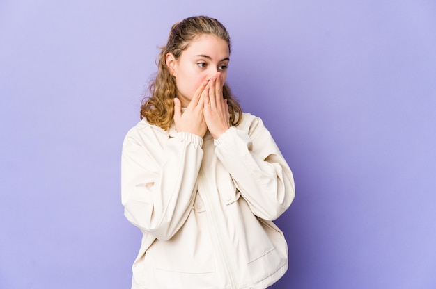 Jonge blanke vrouw op paars doordachte op zoek naar een kopie ruimte die mond met de hand.