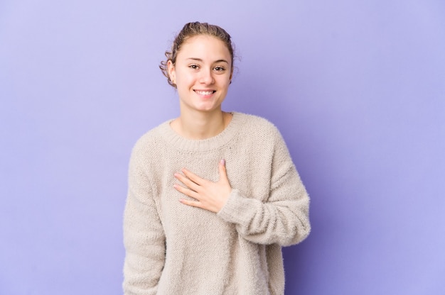 Jonge blanke vrouw op paars lacht hardop hand op de borst te houden.