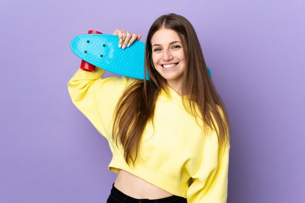 Jonge blanke vrouw op paars met een skate