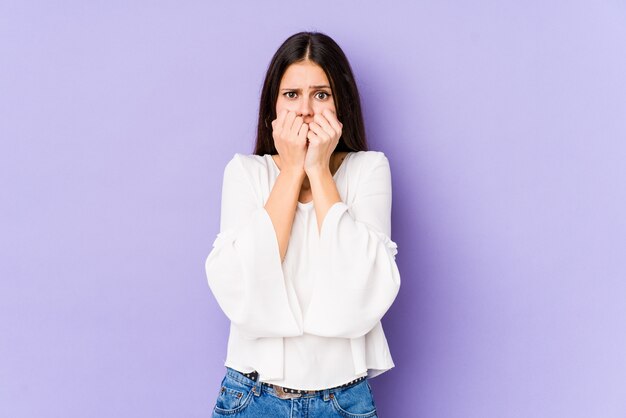 Jonge blanke vrouw op paarse muur bijten nagels, nerveus en erg angstig.