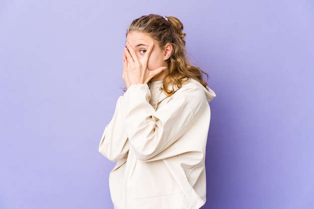 Jonge blanke vrouw op paarse muur knipperen door angstige en nerveuze vingers.