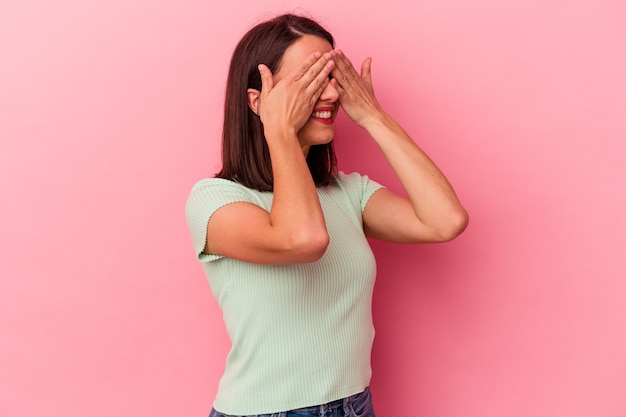 Jonge blanke vrouw op roze achtergrond bang voor ogen met handen.