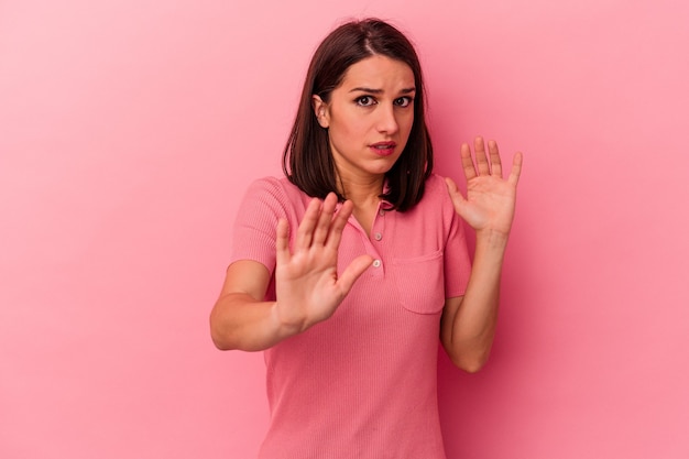 Jonge blanke vrouw op roze achtergrond wordt geschokt door een dreigend gevaar