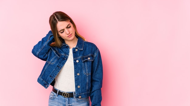 Jonge blanke vrouw op roze muur met nekpijn