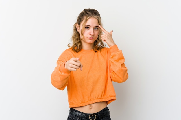 Jonge blanke vrouw op wit muur wijzende tempel met vinger, denken, gericht op een taak.