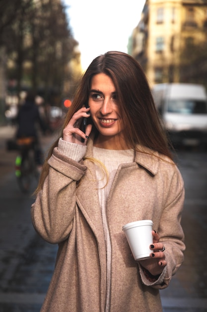 Jonge blanke vrouw praten via de telefoon terwijl het drinken van koffie