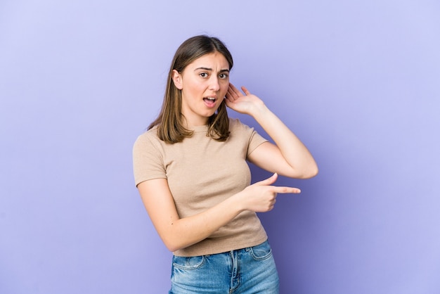 Jonge blanke vrouw probeert een roddel te luisteren.