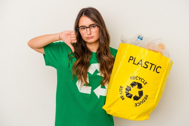 Jonge blanke vrouw recycling een vol plastic geïsoleerd op een witte achtergrond met een afkeer gebaar, duim omlaag. Onenigheid begrip.