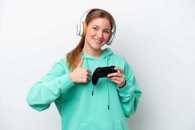 Jonge blanke vrouw spelen met een video game controller geïsoleerd op een witte achtergrond met een duim omhoog gebaar
