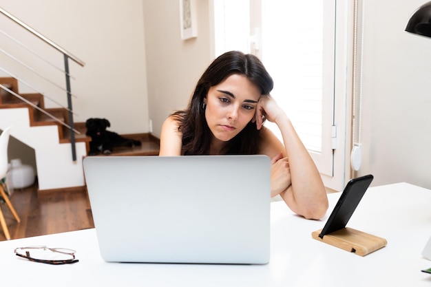 Jonge blanke vrouw verveeld en gefrustreerd voor laptop die thuis werkt. Levensstijlconcept.