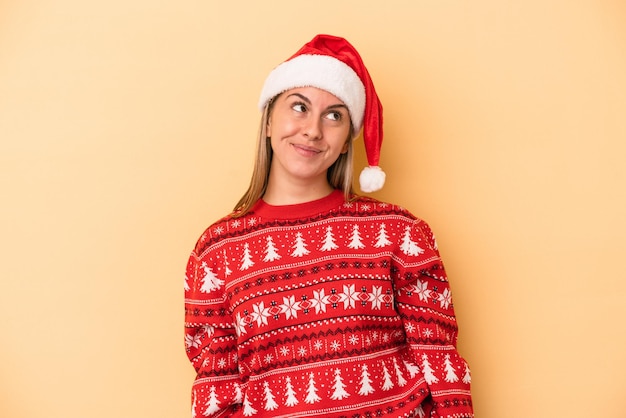 Jonge blanke vrouw viert Kerstmis geïsoleerd op gele achtergrond dromen van het bereiken van doelen en doeleinden