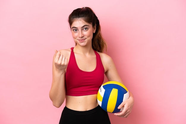 Jonge blanke vrouw volleyballen geïsoleerd op roze achtergrond geld gebaar maken