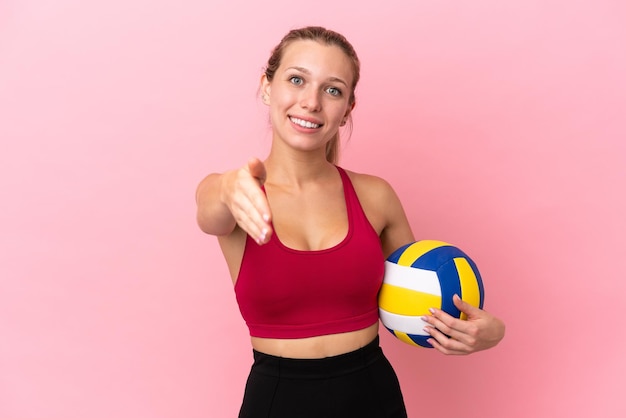 Jonge blanke vrouw volleyballen geïsoleerd op roze achtergrond handen schudden voor het sluiten van een goede deal
