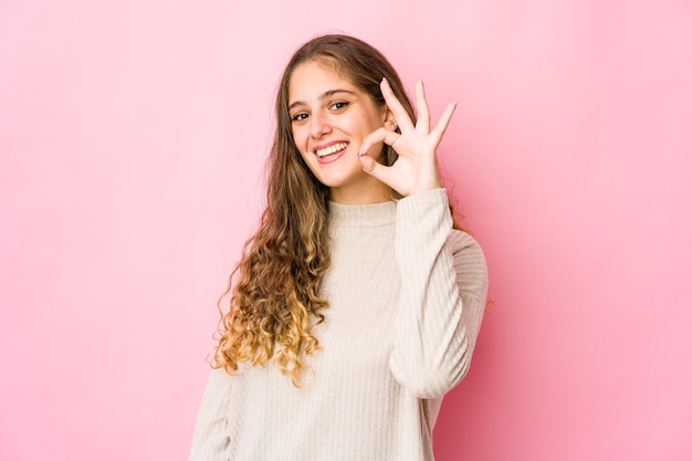 Jonge blanke vrouw vrolijk en zelfverzekerd weergegeven: ok gebaar.