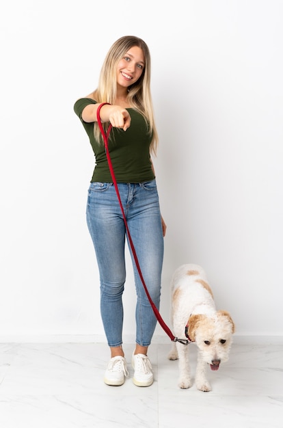 Jonge blanke vrouw wandelen met de hond op wit wijzend front met gelukkige uitdrukking