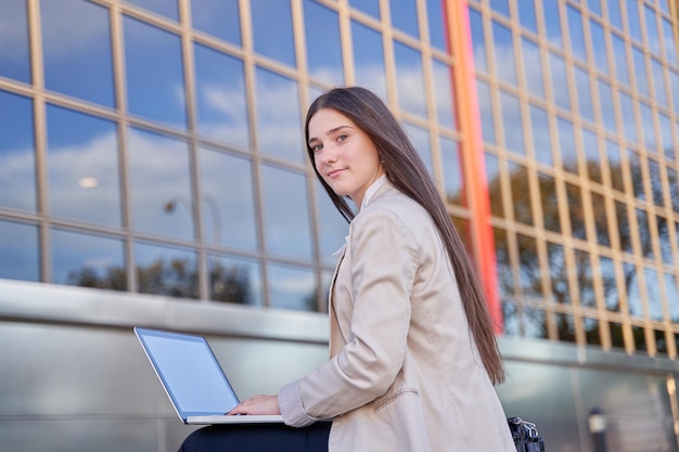 Jonge blanke vrouw zittend op de universiteitscampus met een laptopcomputer