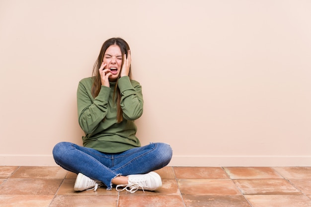 Jonge blanke vrouw zittend op de vloer geïsoleerd jammeren en troosteloos huilen.