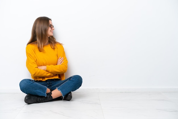 Jonge blanke vrouw zittend op de vloer geïsoleerd op een witte achtergrond in zijpositie