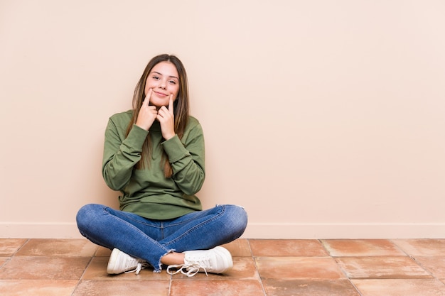 Jonge blanke vrouw zittend op de vloer twijfelde tussen twee opties.