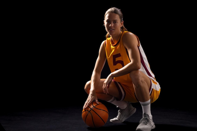 Jonge blanke vrouwelijke basketbalspeler poseert zelfverzekerd in basketbalkleding met een kopieerruimte op