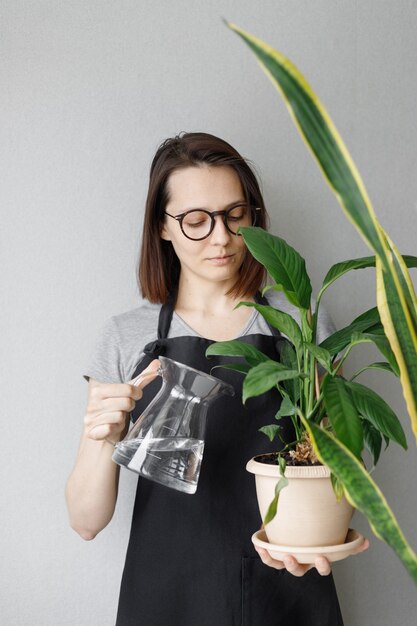 Jonge blanke vrouwelijke bloemist in een t-shirt en een donkere schort in haar huis bloemenwinkel met een mand