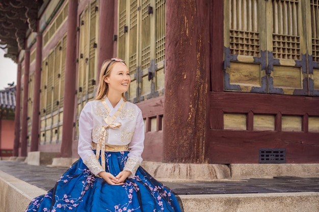 Foto jonge blanke vrouwelijke toerist in hanbok nationale koreaanse jurk in koreaans paleis reizen naar korea concept nationale koreaanse kleding entertainment voor toeristen die nationale koreaanse kleding proberen