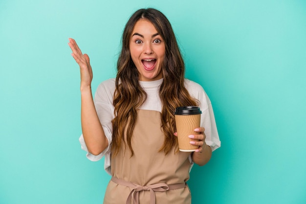 Jonge blanke winkelbediende vrouw met een afhaalmaaltijden koffie geïsoleerd op blauwe achtergrond ontvangen een aangename verrassing, opgewonden en handen opsteken.