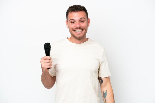 Jonge blanke zanger man oppakken van een microfoon geïsoleerd op een witte achtergrond met verrassing gelaatsuitdrukking
