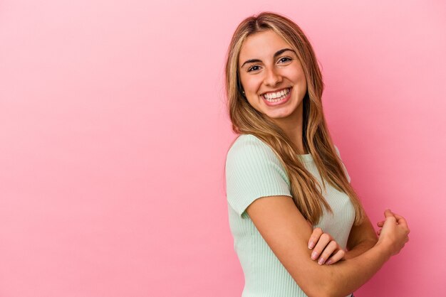 Jonge blonde blanke vrouw die lacht zelfverzekerd met gekruiste armen.