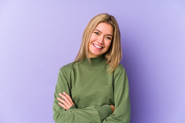 Jonge blonde blanke vrouw die zich zelfverzekerd voelt, armen gekruist met vastberadenheid.