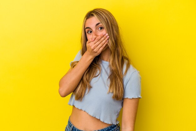 Jonge blonde blanke vrouw geïsoleerd op gele achtergrond bang en bang.