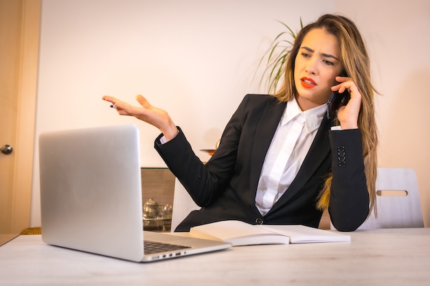 Jonge blonde blanke vrouw met een kop koffie die met de computer werkt