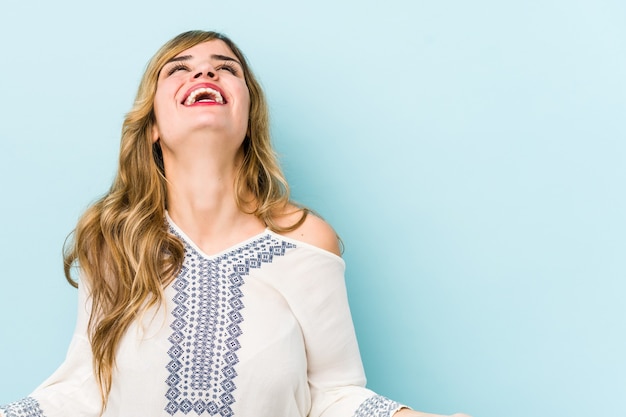 Jonge blonde blanke vrouw ontspannen en gelukkig lachen, nek uitgerekt met tanden.