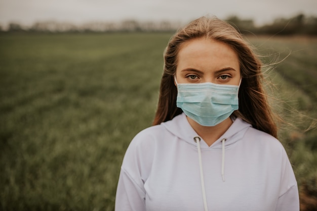 Jonge blonde Europese vrouw in een beschermend masker buitenshuis.