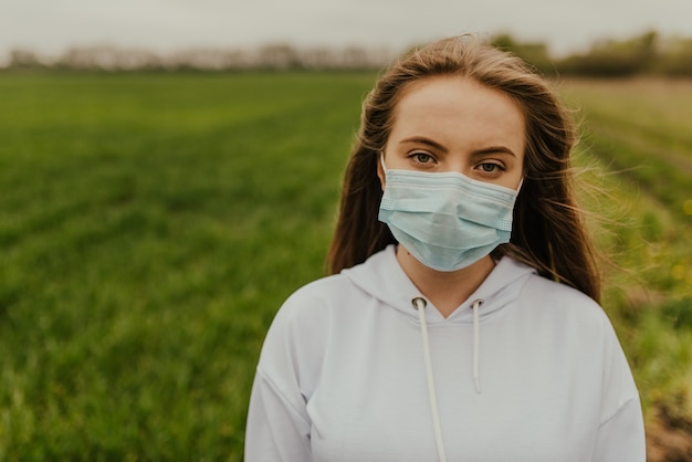 Jonge blonde Europese vrouw in een beschermend masker buitenshuis.