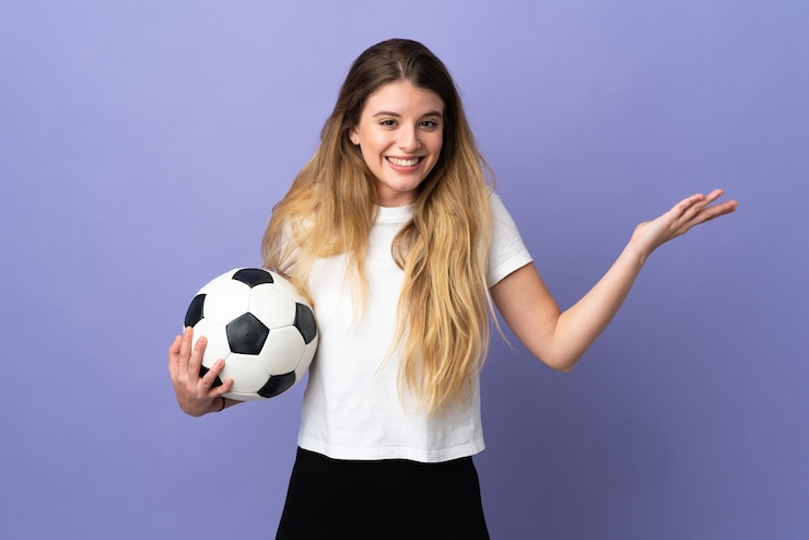 Foto jonge blonde geïsoleerde voetballervrouw wijzend naar de kant om een product te presenteren