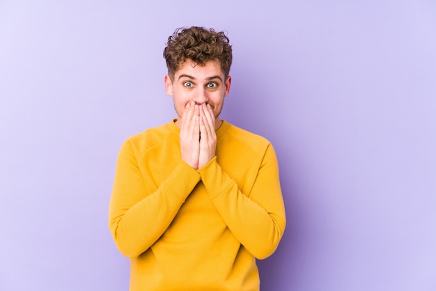 Jonge blonde krullend haar blanke man geïsoleerd lachen om iets, mond bedekken met handen.