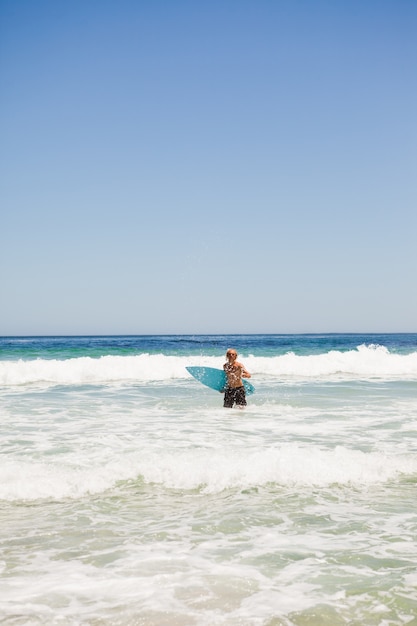 Jonge blonde man die terugkeert naar het strand