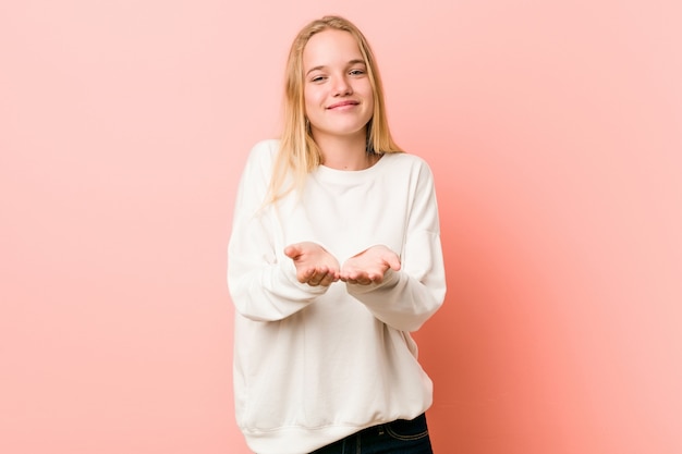 Jonge blonde tienervrouw die iets met palmen houden, die aan camera aanbieden.