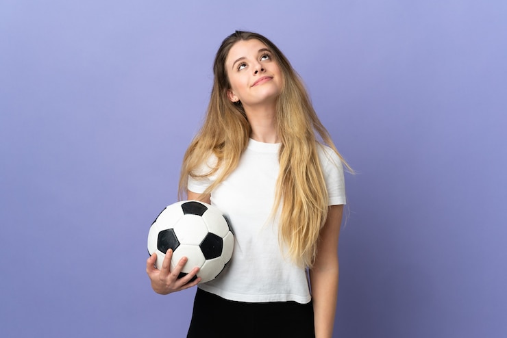 Foto jonge blonde voetbalster vrouw geïsoleerd op paarse ruimte en opzoeken