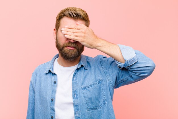 Jonge blonde volwassen mens die ogen behandelen met één hand die bang of angstig voelen, zich afvragen of blind wachten op een verrassing