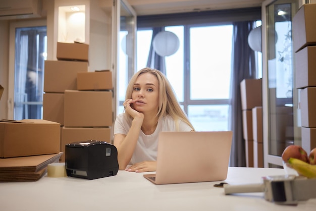 Jonge blonde vrouw barcode printer en dozen op de achtergrond voor marktplaatsen