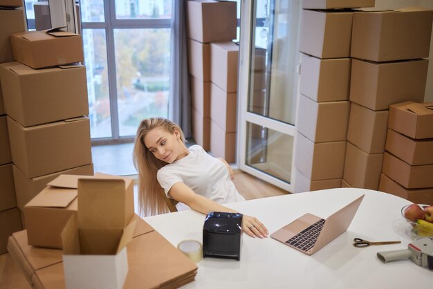 Jonge blonde vrouw barcode printer en dozen op de achtergrond voor marktplaatsen