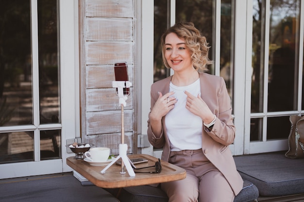 Jonge blonde vrouw blogger werkt in een straatcafé op een mobiele telefoon