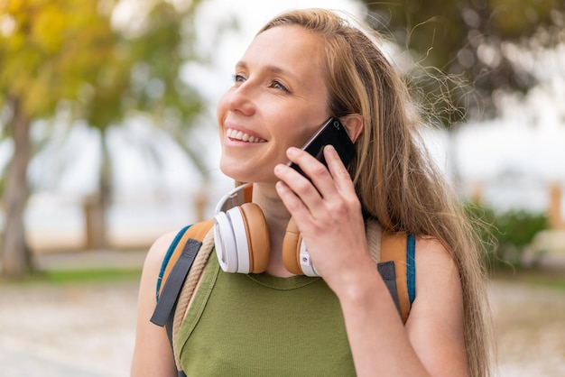 Foto jonge blonde vrouw buiten met een mobiele telefoon.