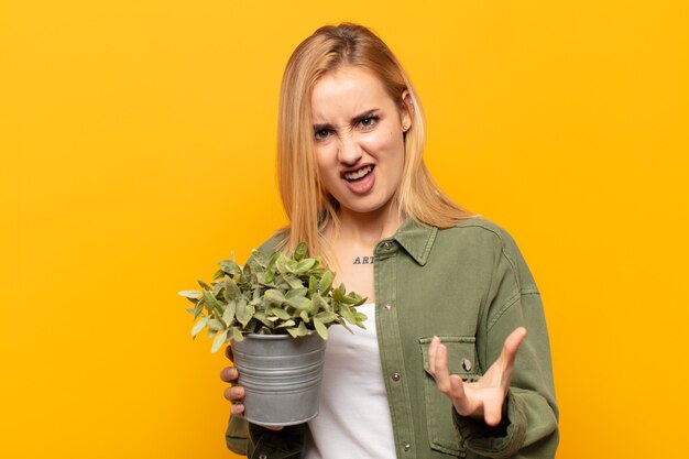 Jonge blonde vrouw die boos, geïrriteerd en gefrustreerd kijkt, schreeuwend wtf of wat is er mis met je