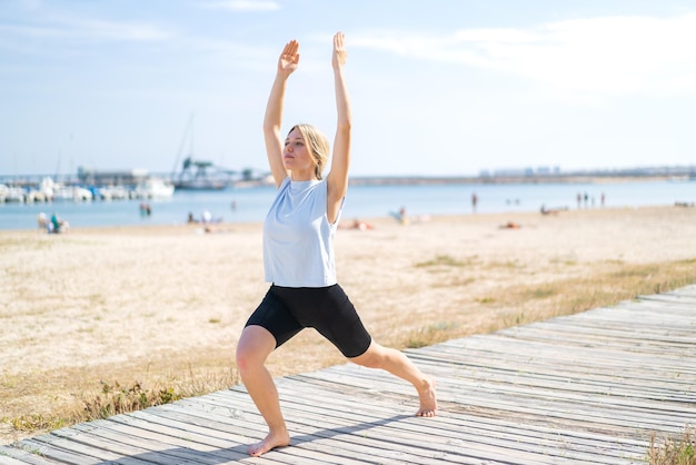 Jonge blonde vrouw die buiten yoga doet