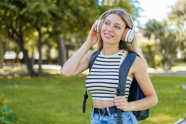 Jonge blonde vrouw die buitenshuis muziek luistert